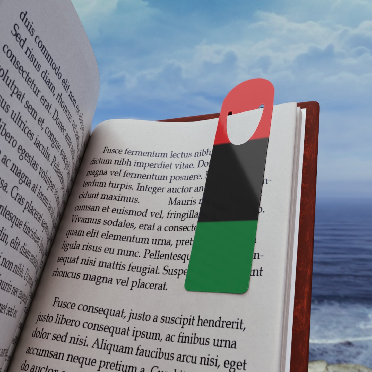 Pan-African Bookmark - Vibrant & Durable for Readers placed in an open book by the ocean, showcasing its colorful design and perfect fit for book lovers.