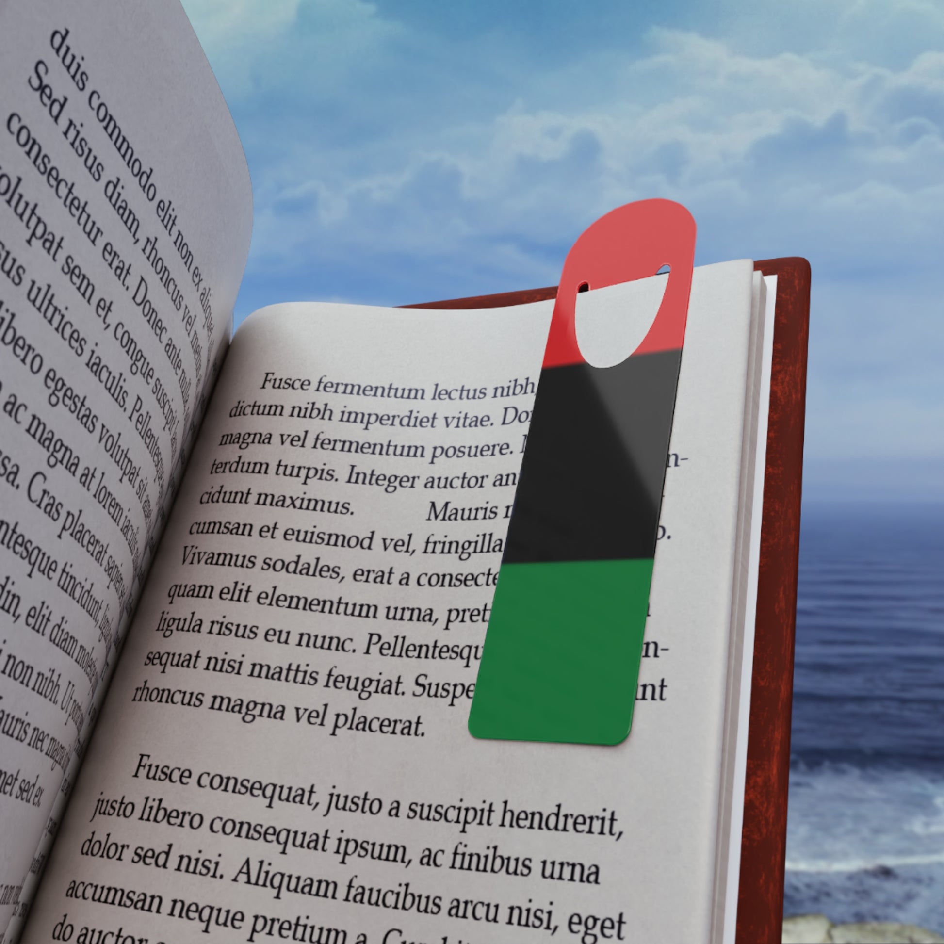 Pan-African Bookmark - Vibrant & Durable for Readers placed in an open book by the ocean, showcasing its colorful design and perfect fit for book lovers.
